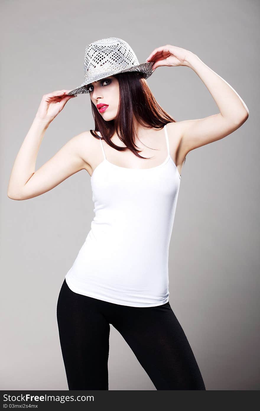 Attractive brunette in a white t shirt and black tights wearing a hat. Attractive brunette in a white t shirt and black tights wearing a hat