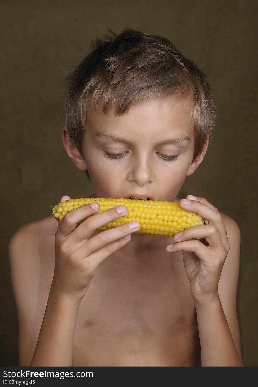 The boy with appetite eats the boiled corn.