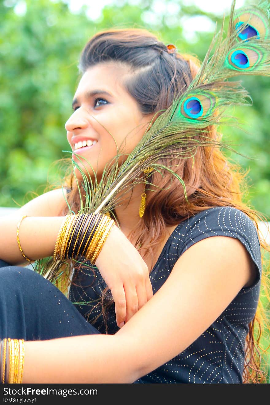 Young Pakistani model posing with traditional peacock feathers and gold ornaments. Young Pakistani model posing with traditional peacock feathers and gold ornaments