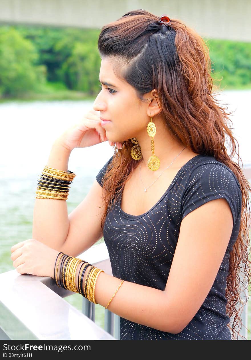 A young Pakistani model in deep thoughts wearing traditional gold jewellery. A young Pakistani model in deep thoughts wearing traditional gold jewellery