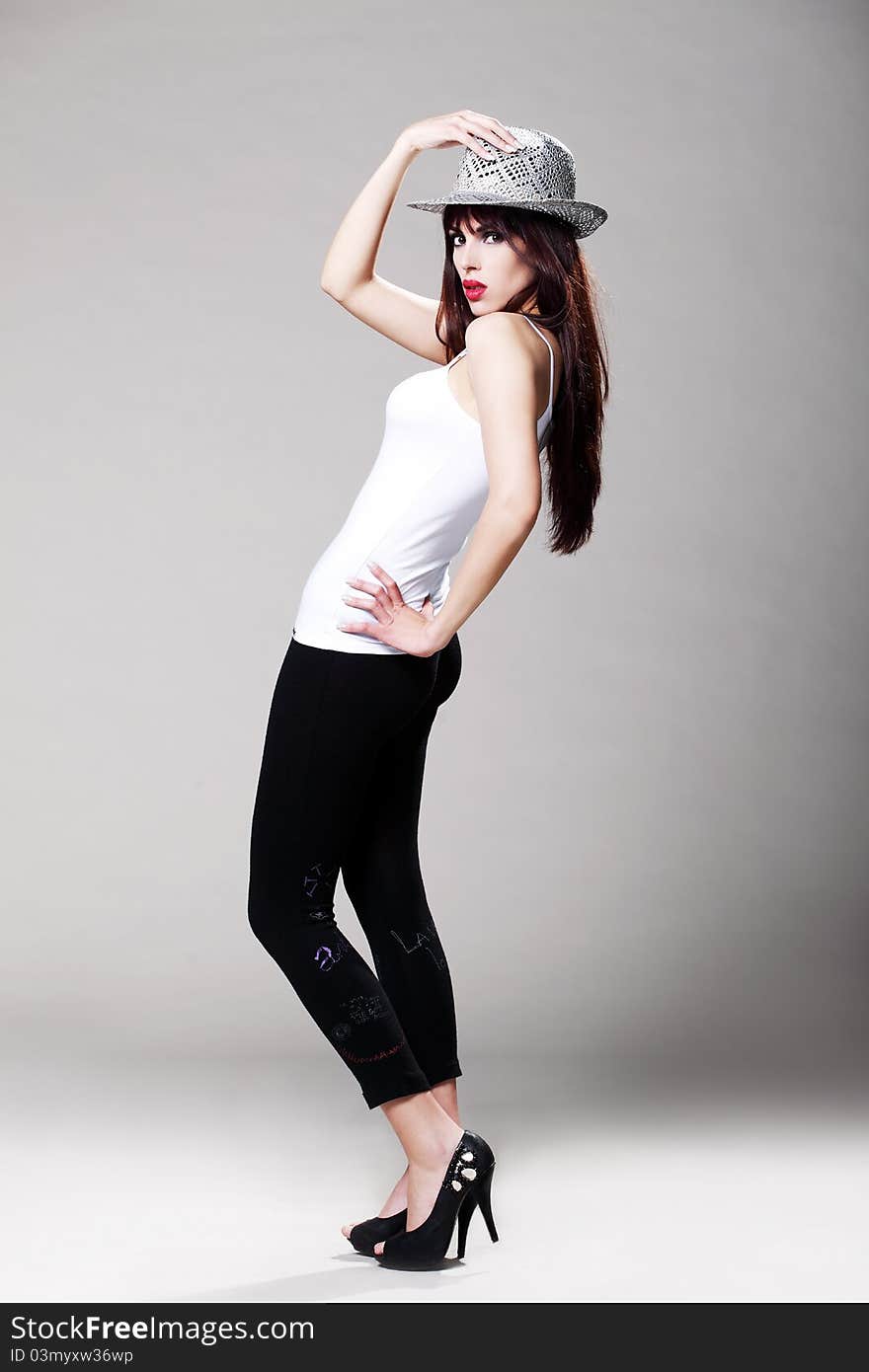 Attractive brunette in a white t shirt and black tights wearing a hat. Attractive brunette in a white t shirt and black tights wearing a hat