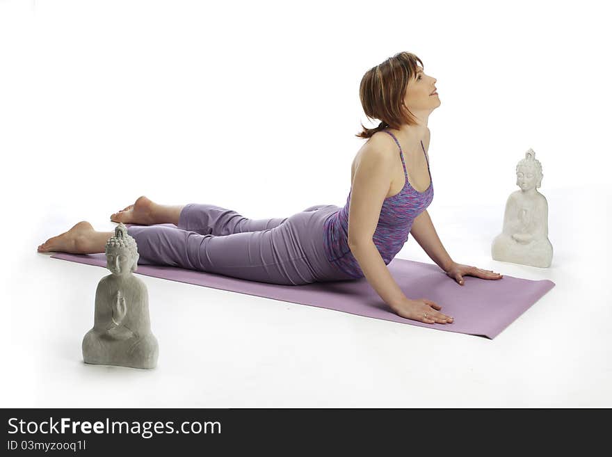 Young early pregnant woman practicing yoga with two buda statues by her sides. Young early pregnant woman practicing yoga with two buda statues by her sides