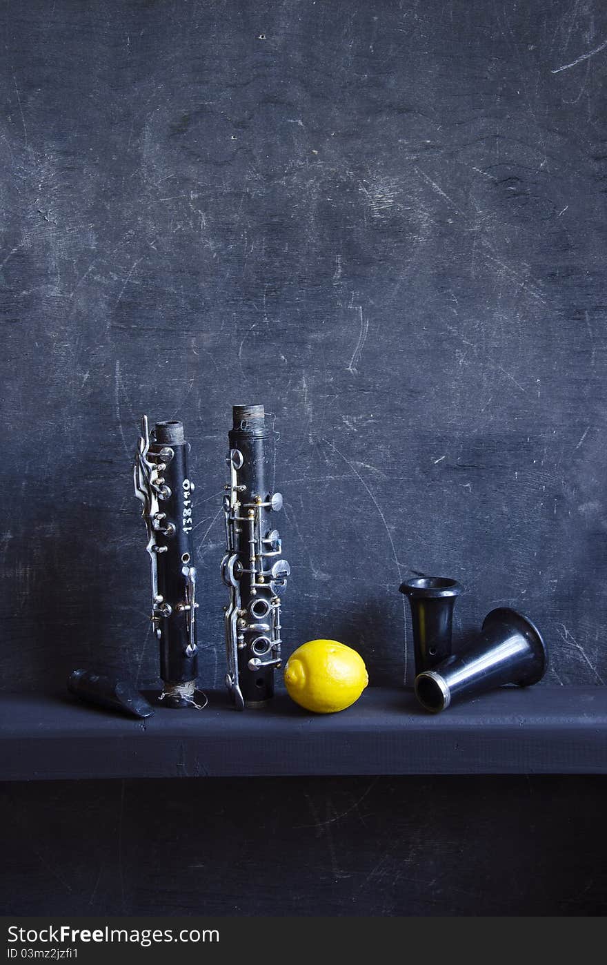 Black still-life with lemon and vintage musical instrument