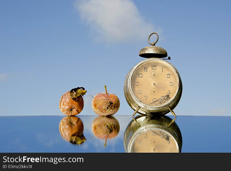 Vintage clock and rotten apples on mirror