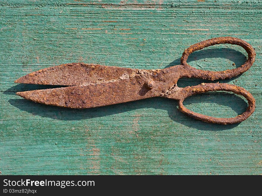 Rusty vintage shears on green wooden background