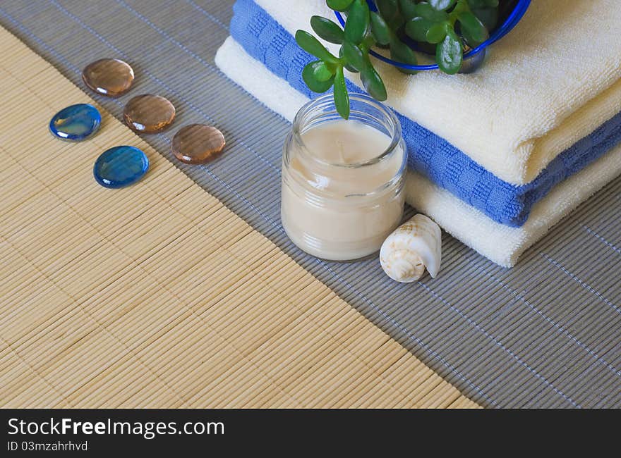 Towels and candles on a woven mat (with focus on candle and shell). Towels and candles on a woven mat (with focus on candle and shell)