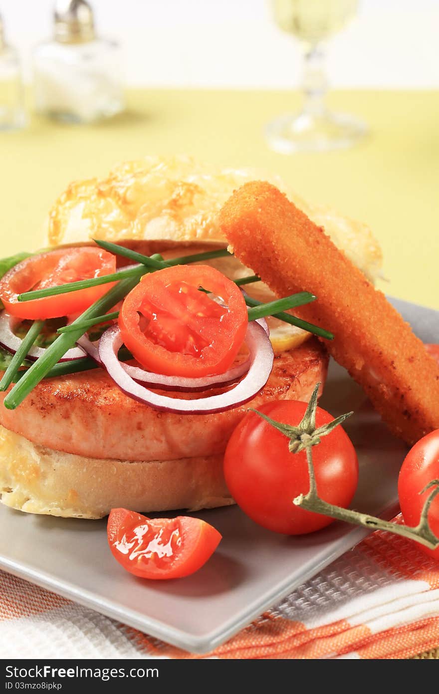 Roasted salmon patty in cheese-topped bun and vegetable garnish. Roasted salmon patty in cheese-topped bun and vegetable garnish