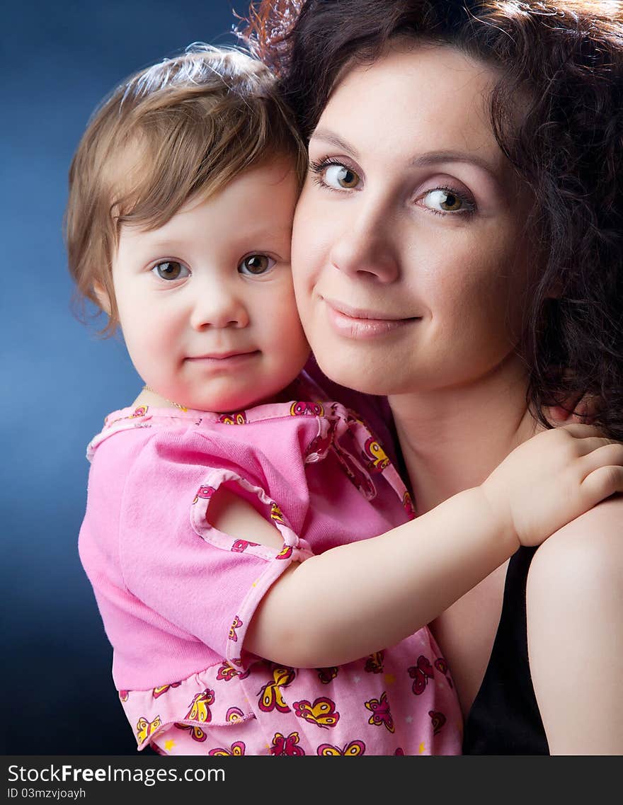 Close-up portrait of beautiful mother with cute young girl on dark background. Close-up portrait of beautiful mother with cute young girl on dark background