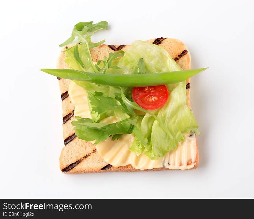 Slice of toasted bread with butter and fresh vegetables. Slice of toasted bread with butter and fresh vegetables