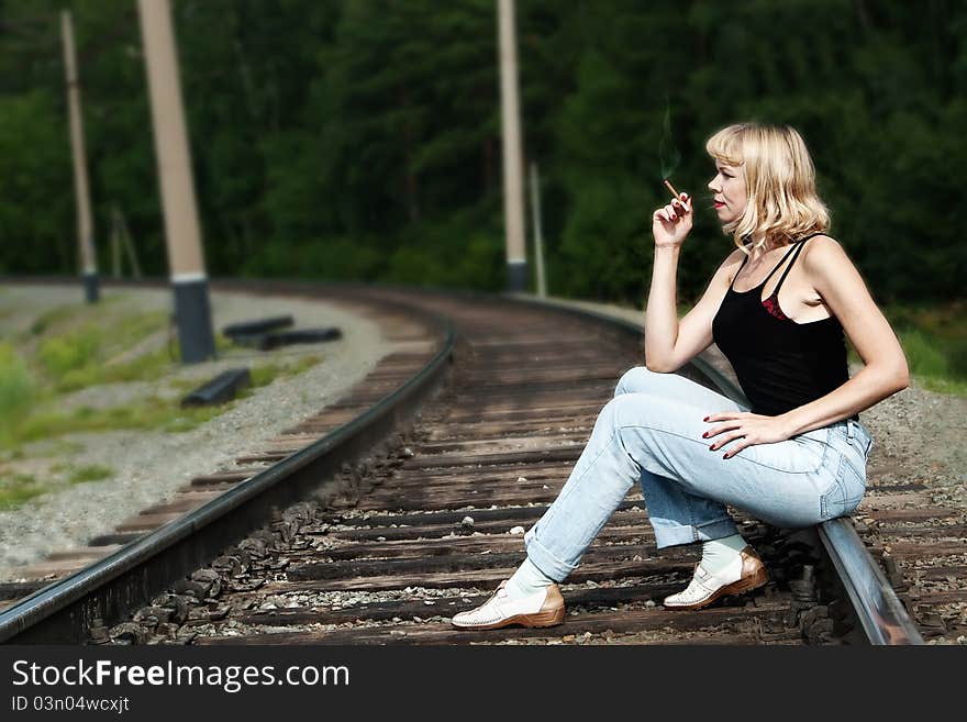 Sexy woman seating on railway and smoking cigaret