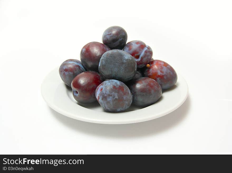 Ripe plums on porcelain plate