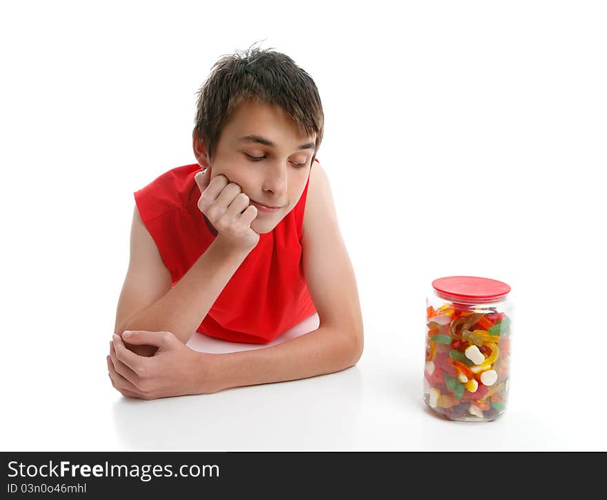 A boy ponders whether to open a jar of assorted confectionery.  White background. A boy ponders whether to open a jar of assorted confectionery.  White background.