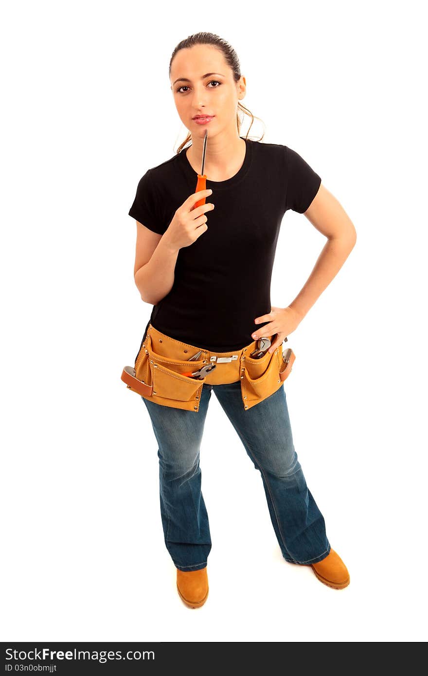 Young female dressed in black top blue jeans waering a tool belt holding a screwdriver on a white isolated background. Young female dressed in black top blue jeans waering a tool belt holding a screwdriver on a white isolated background