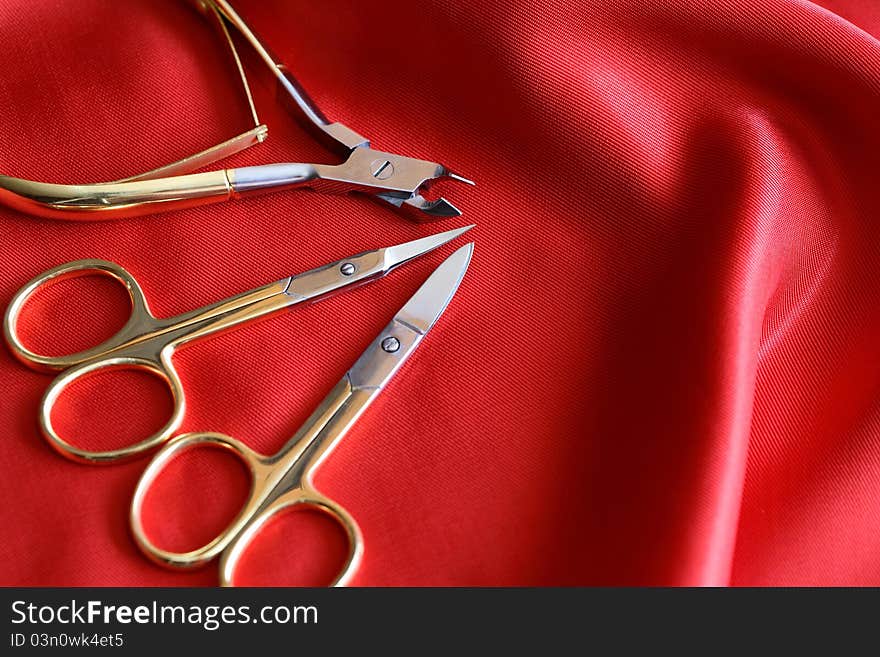 Modern golden manicure or pedicure set on red silk background. Modern golden manicure or pedicure set on red silk background