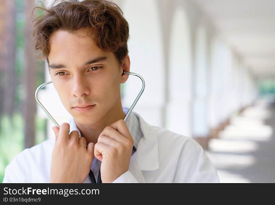 Photo of the young serious doctor outdoors with copy space