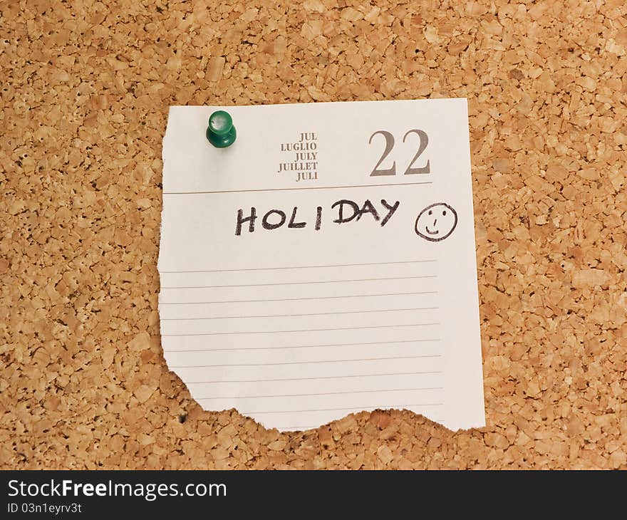 Holiday reminder on cork board with green push pin