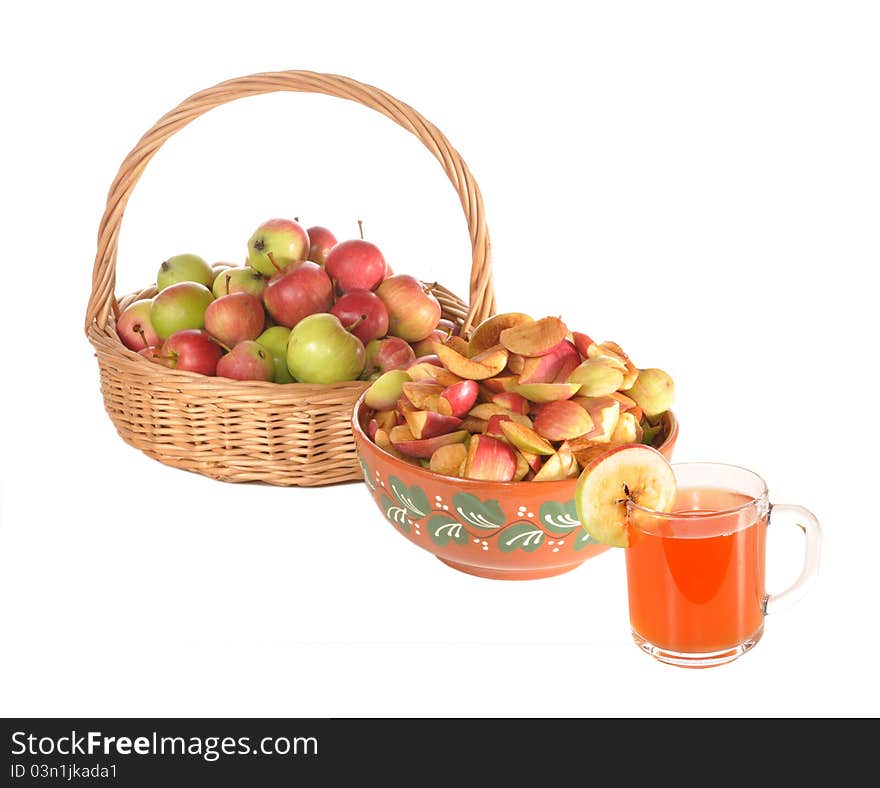 Apples lie in a basket, slices of apples in a ceramic bowl and a glass of apple juice stand on a table. Apples lie in a basket, slices of apples in a ceramic bowl and a glass of apple juice stand on a table