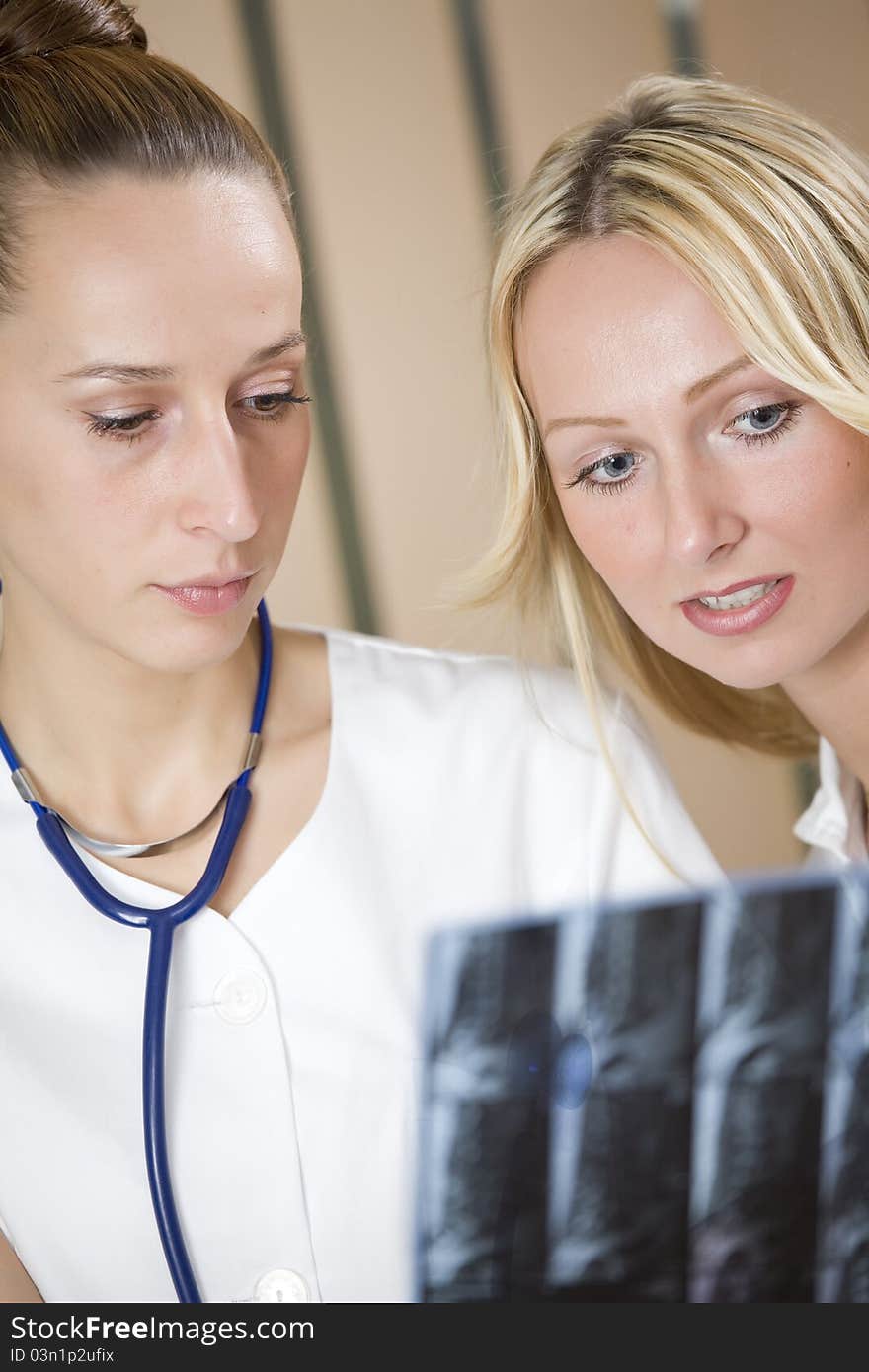 Two women doctors examining film scans of patient spine. Two women doctors examining film scans of patient spine.