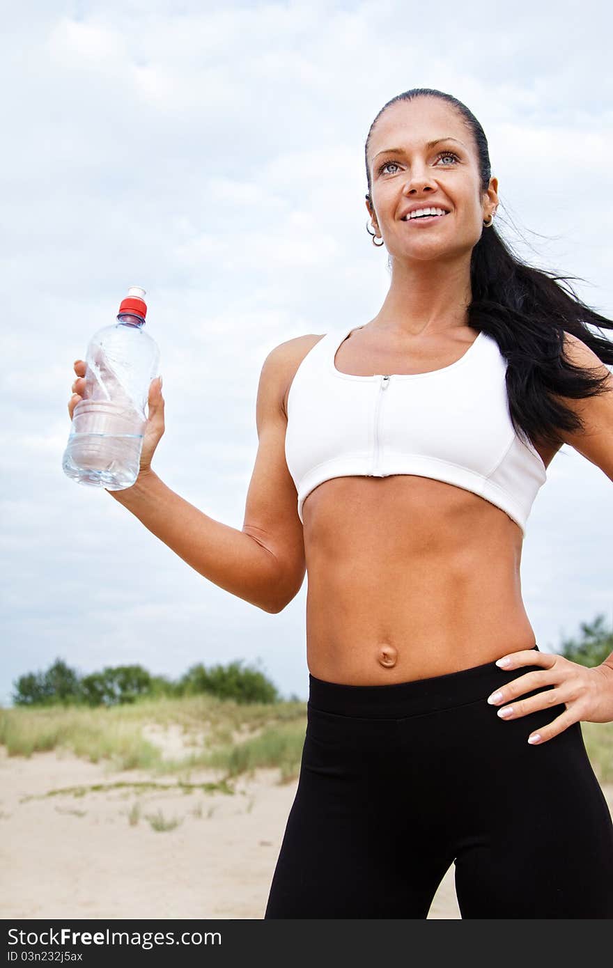 Young woman drinking water after fitness exercise