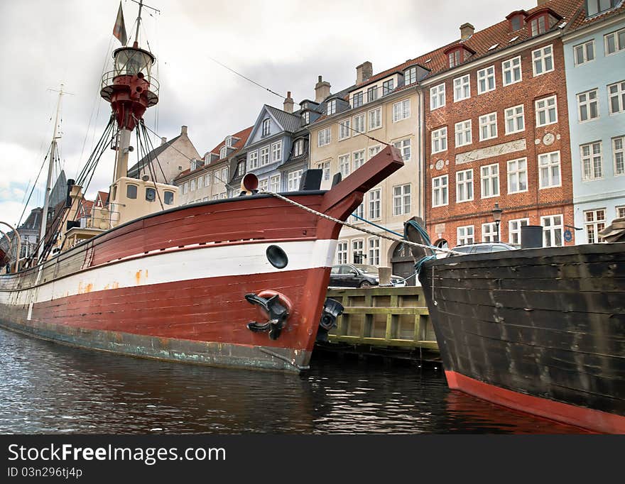 Some boats lying in the water next to houses in Copenhagen, Denmark