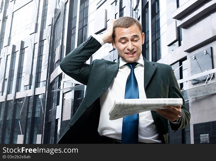 Young businessman reading a daily newspaper and holding his head. Young businessman reading a daily newspaper and holding his head