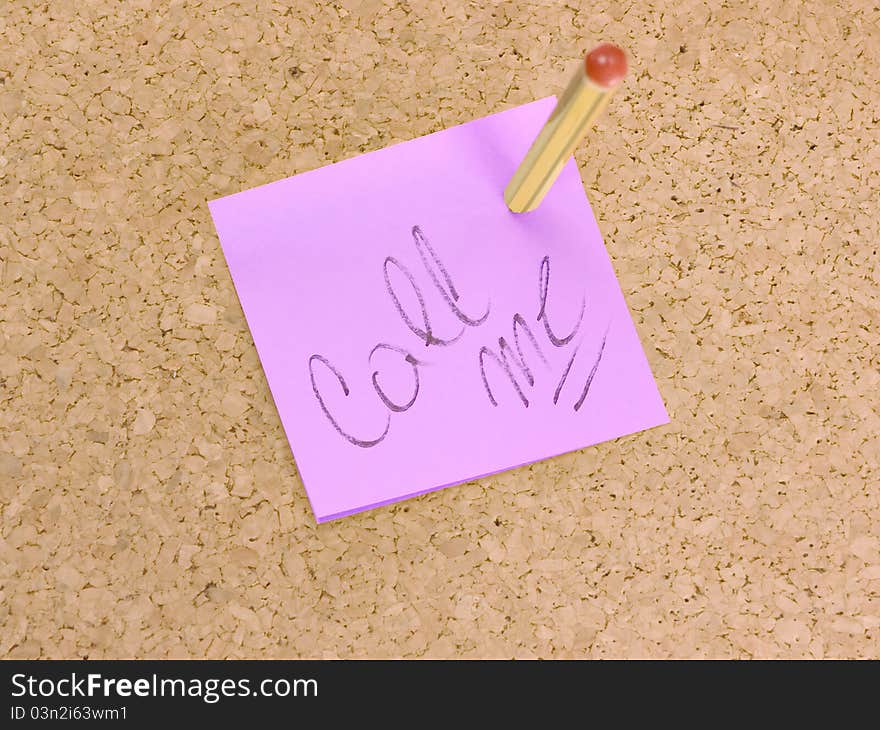 Pink small sticky note on an office cork bulletin board. Call me! Urgent telephone contact needed.