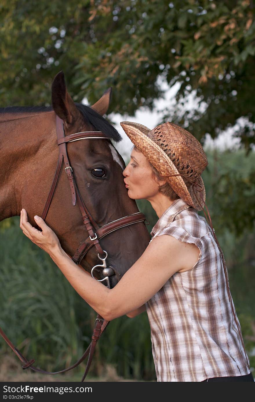 Woman in hat kissing the horse.