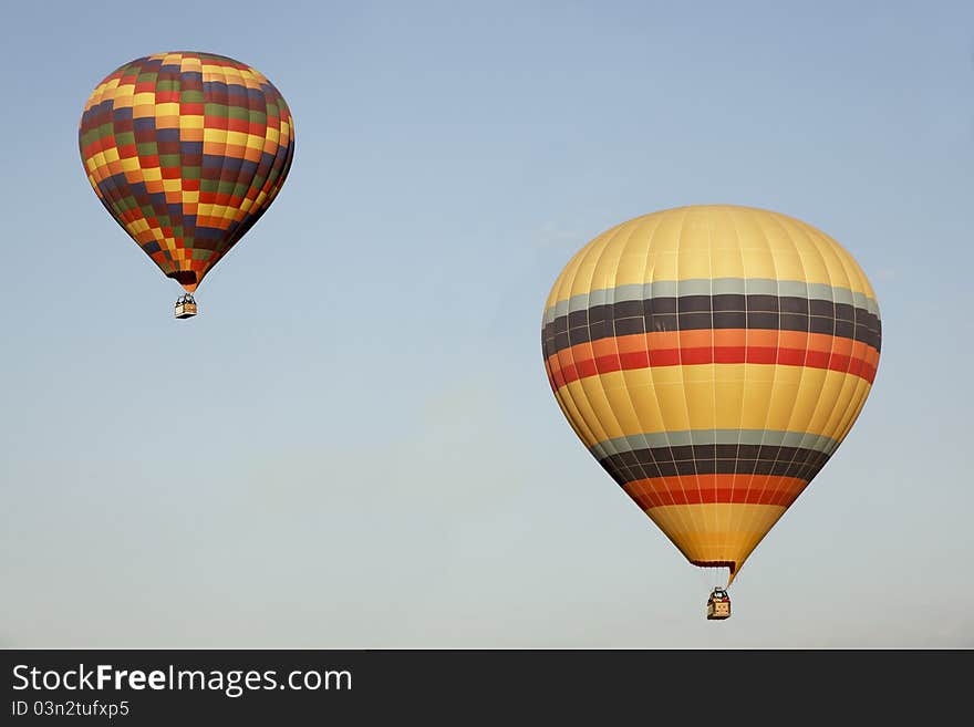 Two multi-colored balloons blue sky