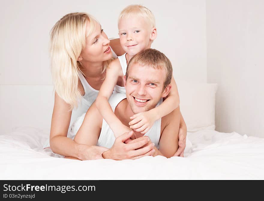 Happy family; mother ,father and their son on the bed at home. Happy family; mother ,father and their son on the bed at home