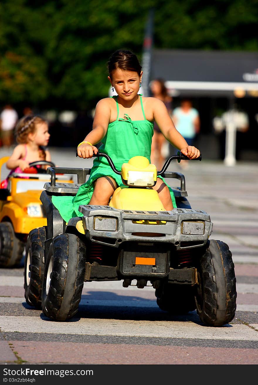 Little girls driving toy atv (battery operated cars) outdoor. Little girls driving toy atv (battery operated cars) outdoor