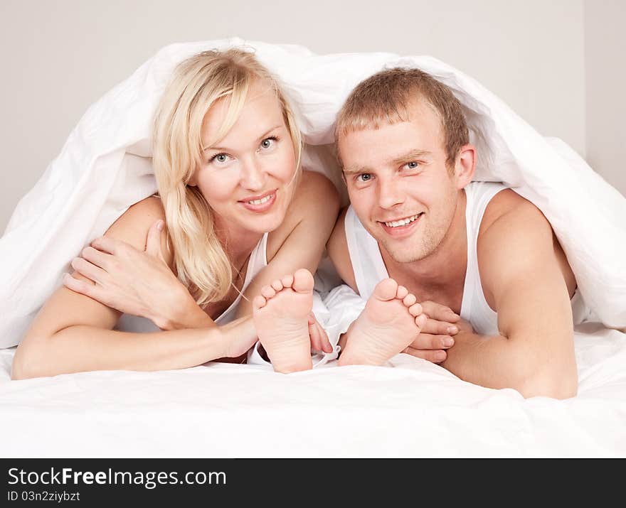 Happy family; mother ,father and their son under the balnket in  bed at home. Happy family; mother ,father and their son under the balnket in  bed at home