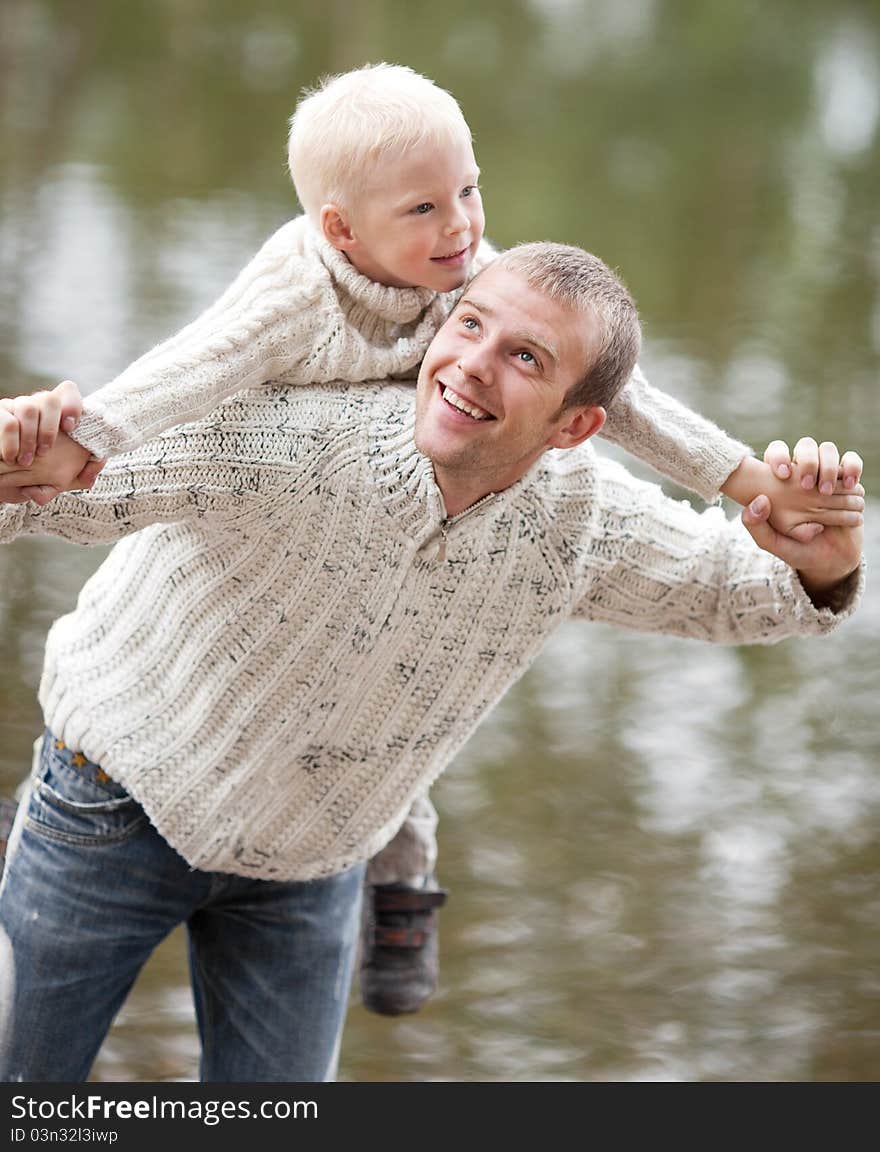 Happy  family; young father and his five year old son near the lake outdoor on a summer day (focus on the men). Happy  family; young father and his five year old son near the lake outdoor on a summer day (focus on the men)