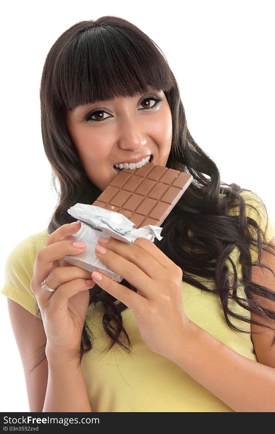 A young pretty woman biting into a block of fruit and nut fine chocolate. White background. A young pretty woman biting into a block of fruit and nut fine chocolate. White background.