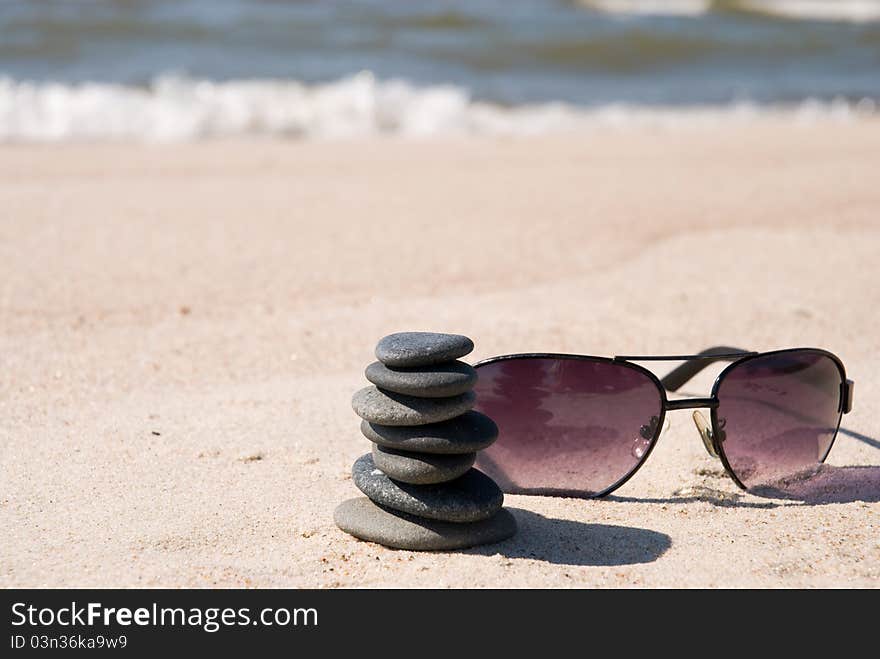 Pebble stack and sunglasse on the seashore