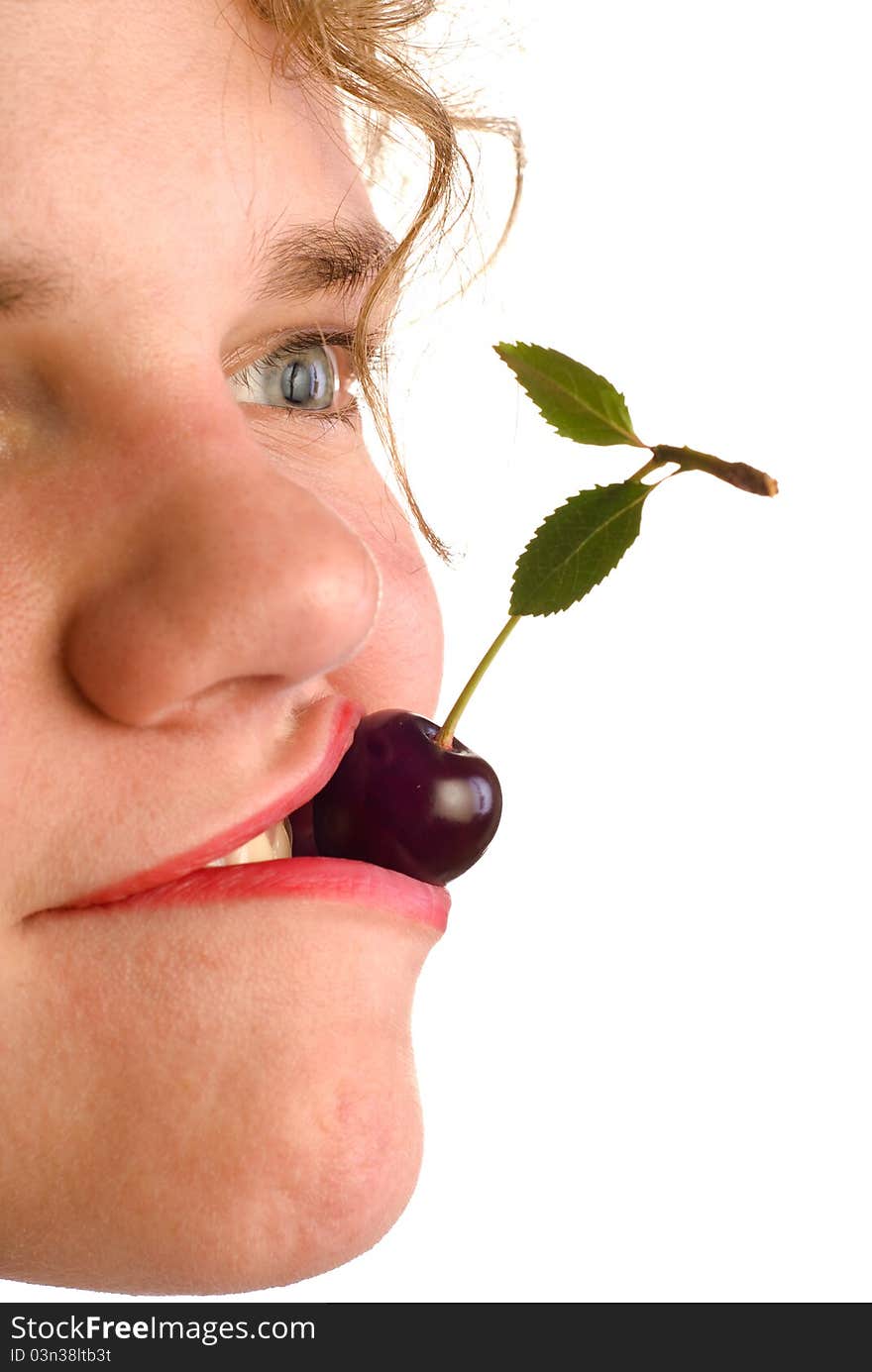 Young woman holding cherry in mouth on white background