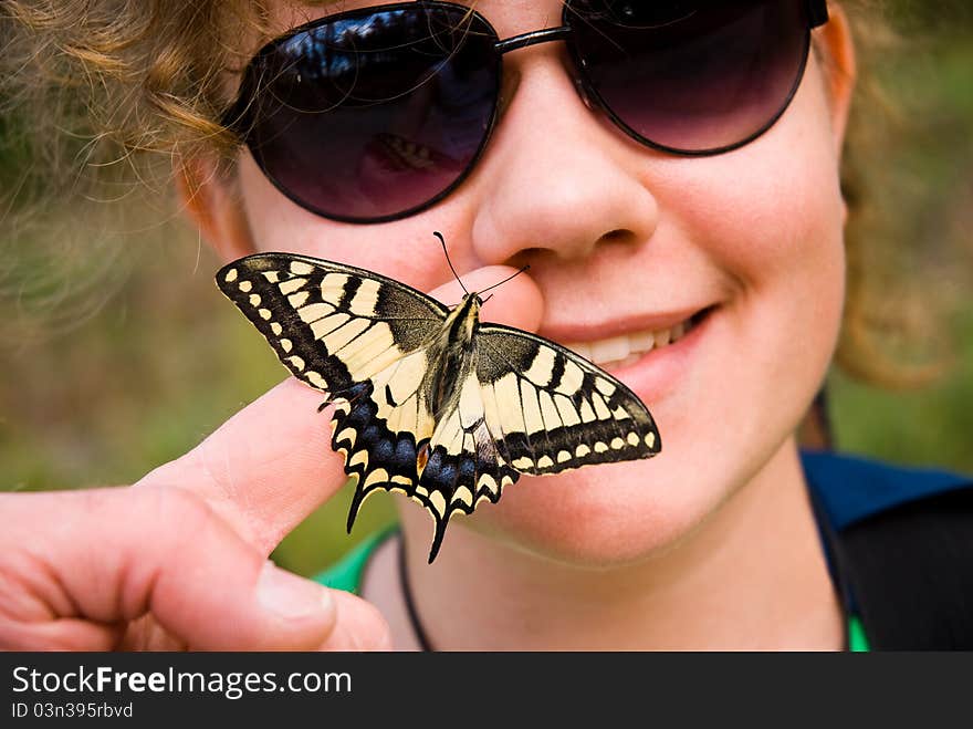 Butterfly sitting on a finger and girls face in the background. Butterfly sitting on a finger and girls face in the background