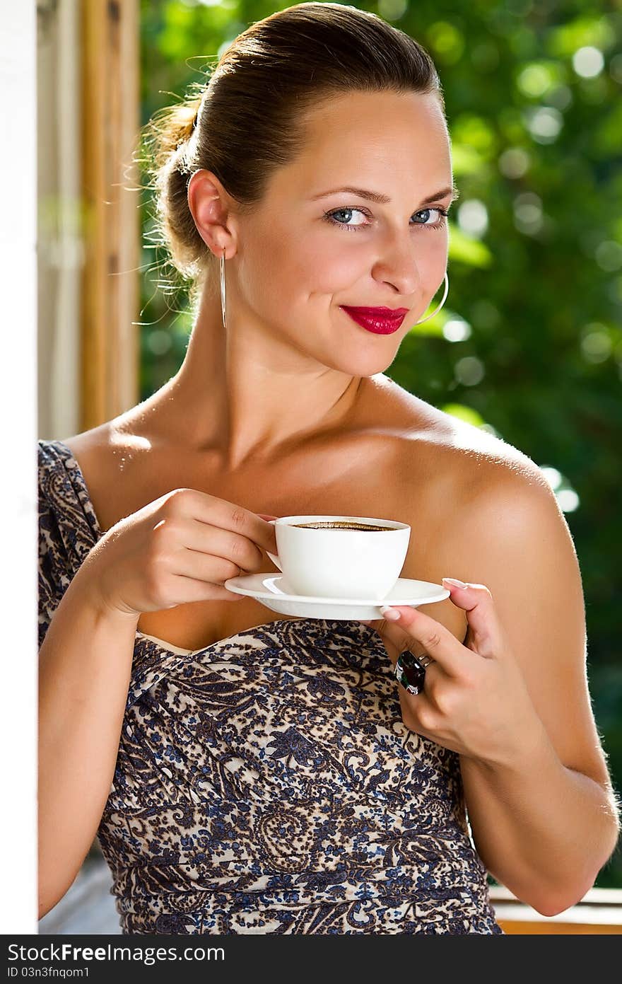 A young attractive woman with a cup of coffe near the window