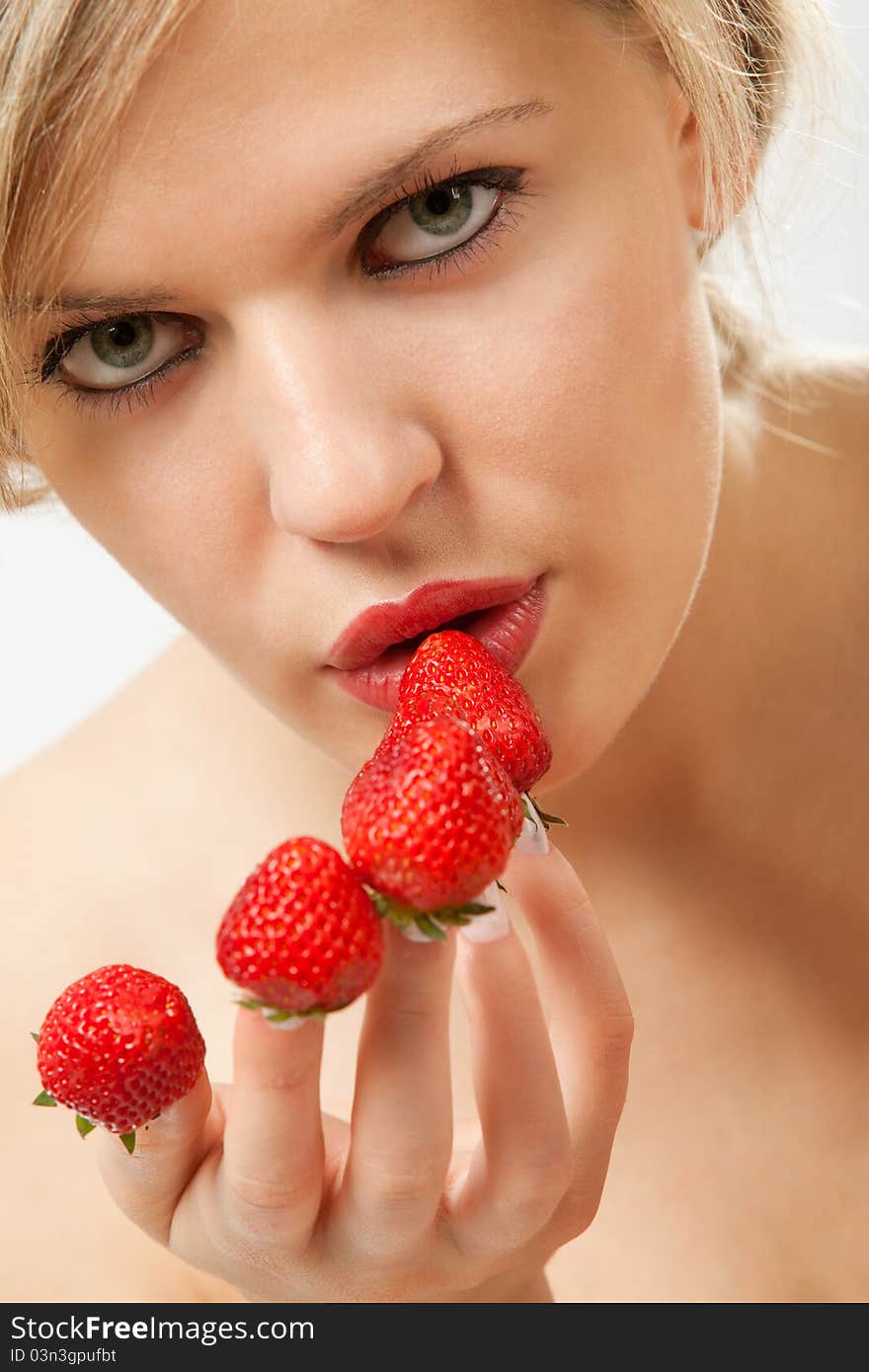 young woman with red strawberries picked on fingertips isolated on white background