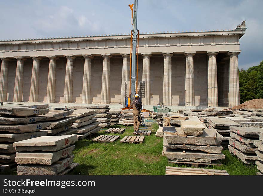 Man working in a construction site with temple in the background. Man working in a construction site with temple in the background