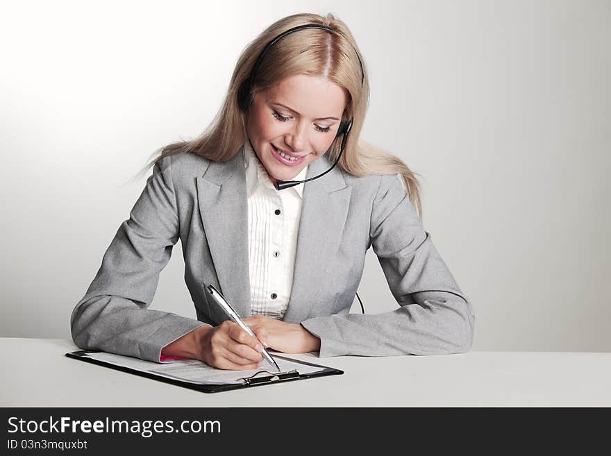 Business woman in a headset writing in notebook. Business woman in a headset writing in notebook