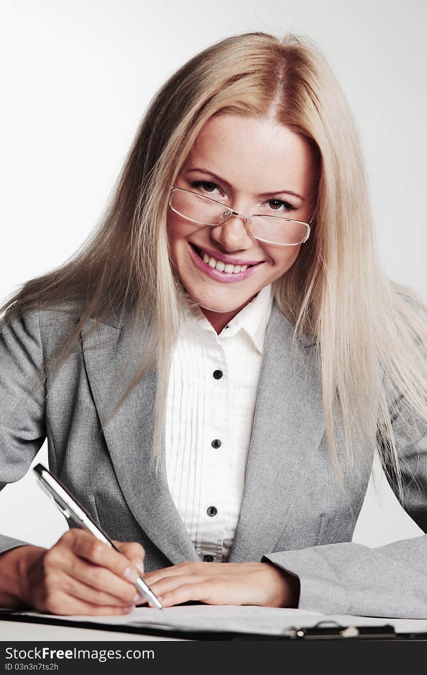 Business woman writing in notebook on a gray background