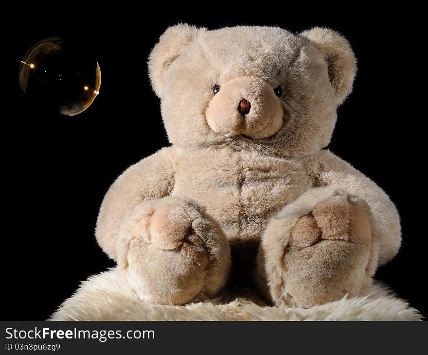 Plush teddy bear toy with bubble on black background