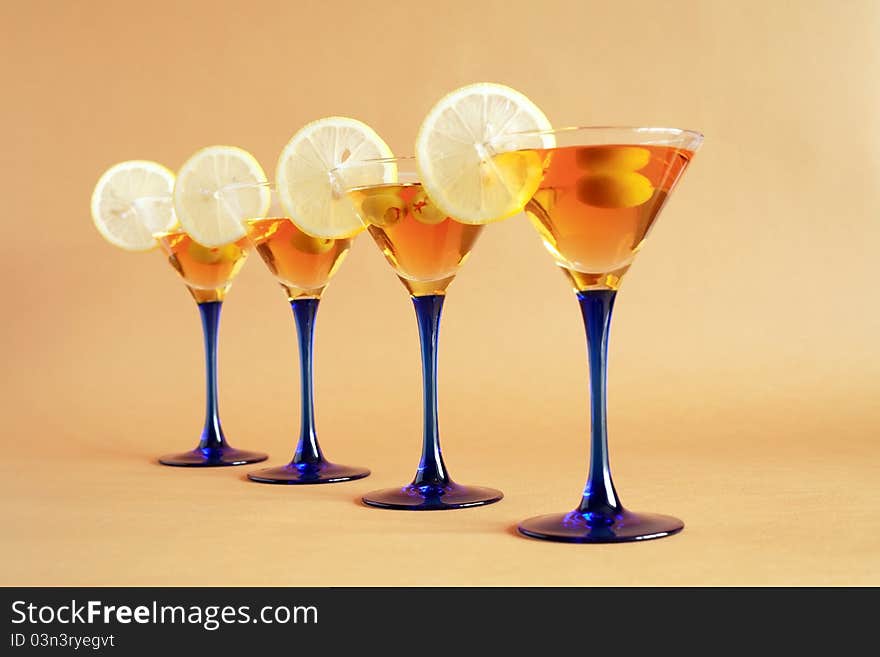 Four martini glasses with lemon and olives standing in a row. Four martini glasses with lemon and olives standing in a row