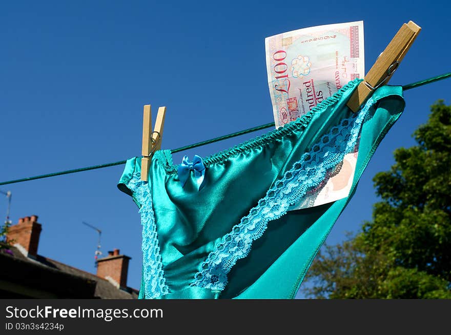 Silk and lace panties with a one hundred pound note sterling, on a respectable suburban washing line hinting at prostitution. Silk and lace panties with a one hundred pound note sterling, on a respectable suburban washing line hinting at prostitution.