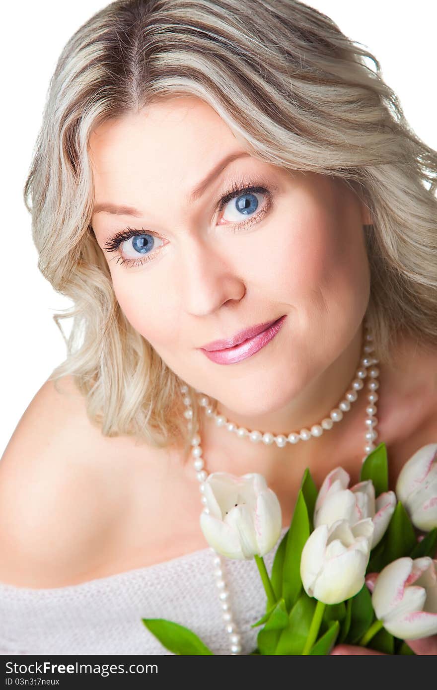 Close-up portrait of charming young blonde woman with blue eyes holding bouquet of gentle tulips and wearing woolen shawl on isolated white background. Close-up portrait of charming young blonde woman with blue eyes holding bouquet of gentle tulips and wearing woolen shawl on isolated white background