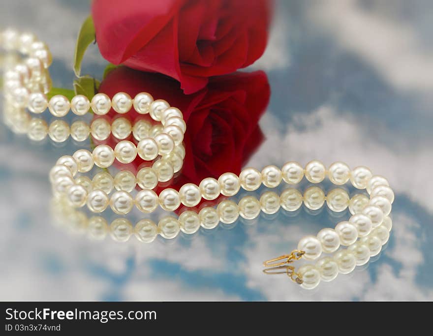 Elegant pearls over glass with clouds and rose very shallow depth of field. Elegant pearls over glass with clouds and rose very shallow depth of field