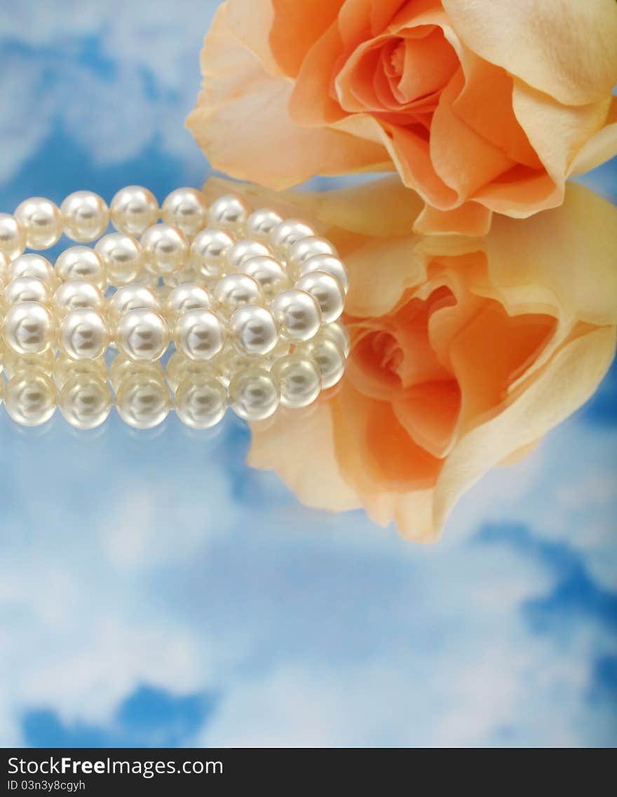 Elegant pearls over glass with clouds and rose very shallow depth of field