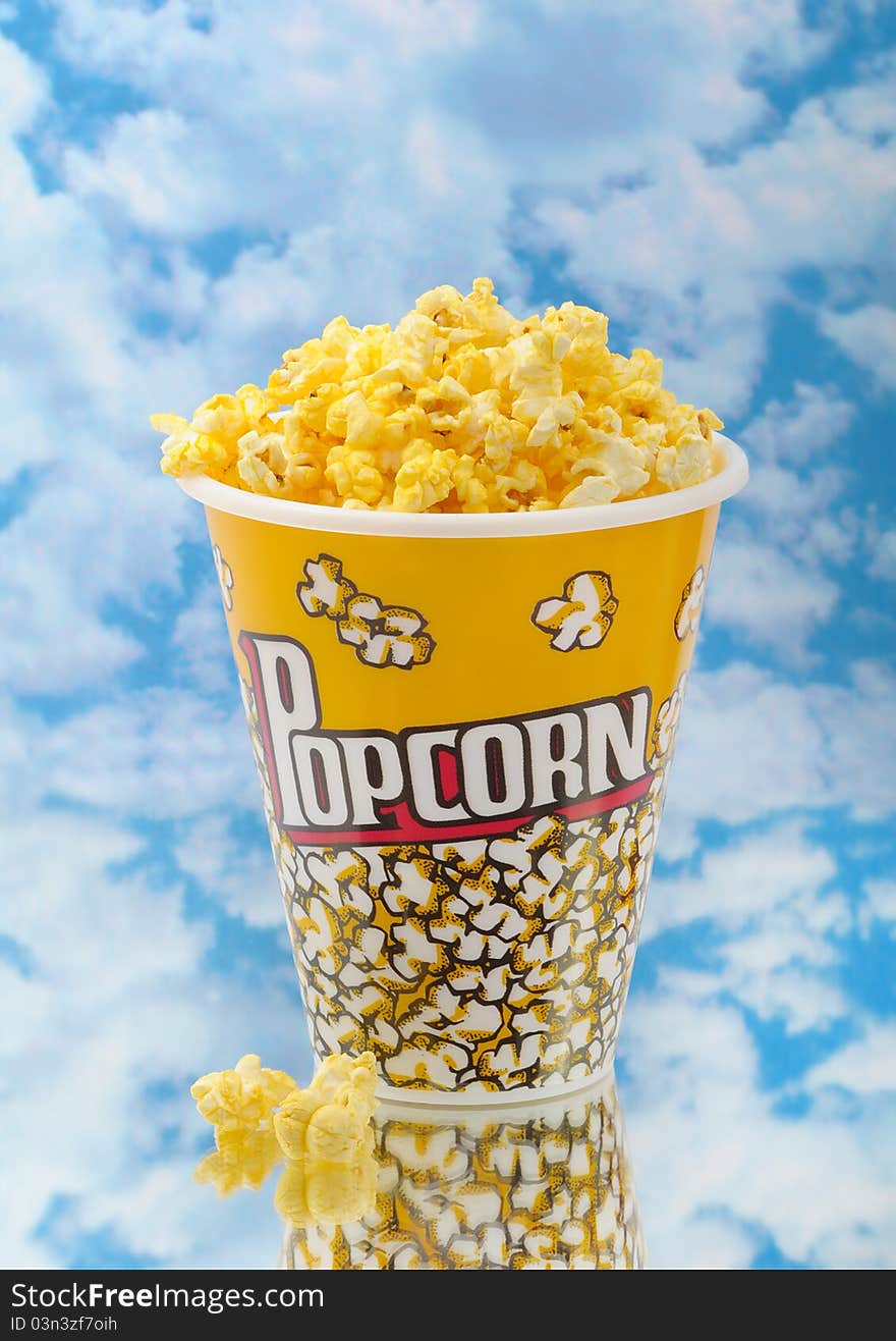 Popcorn on glass with cloud background and container