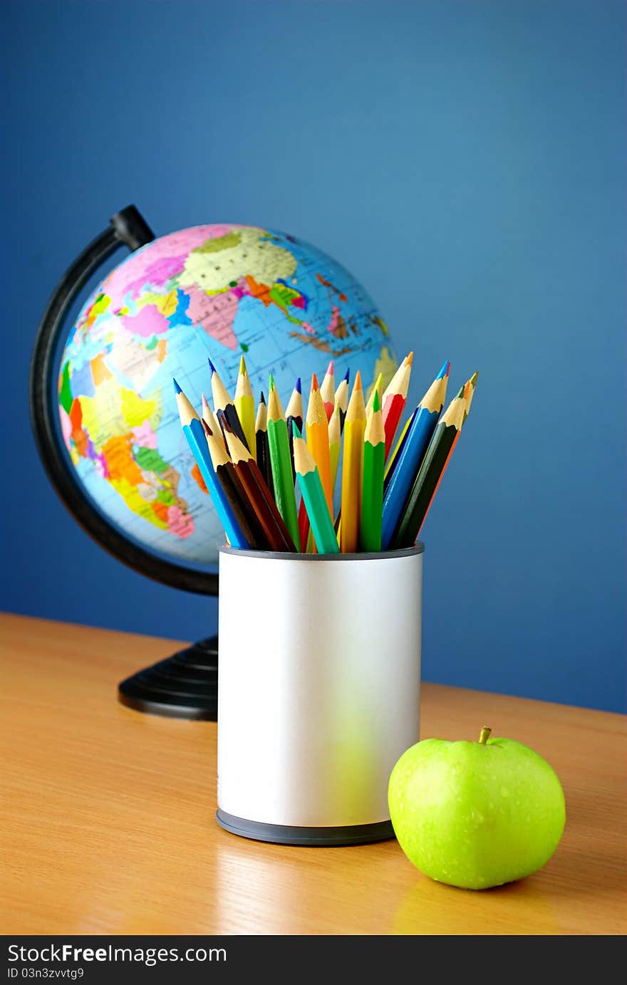 Globe, pencils and an apple on a blue background. Globe, pencils and an apple on a blue background