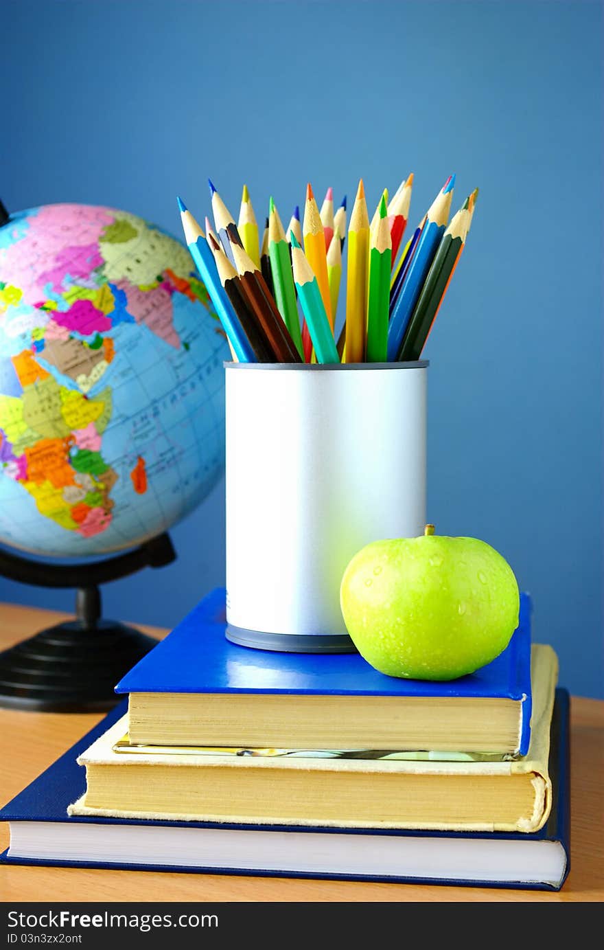 Globe, pencils and an apple on a blue background. Globe, pencils and an apple on a blue background